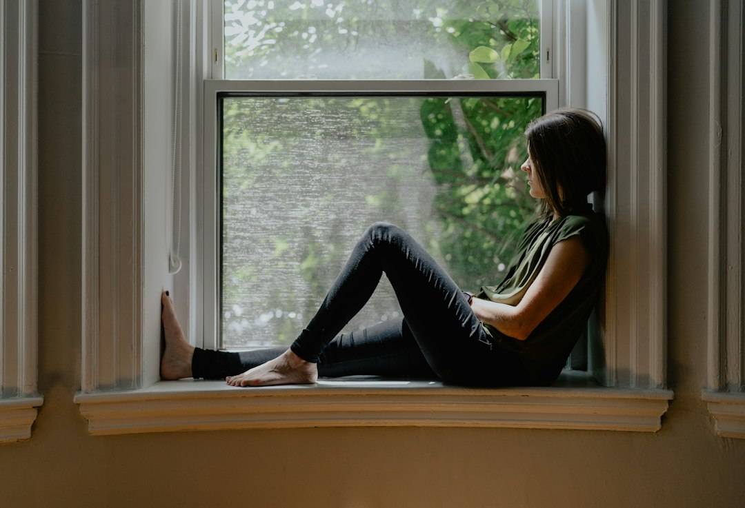 A woman sitting quietly by a window, representing emotional reflection and recovery