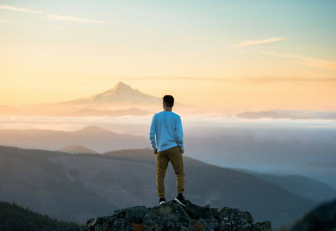 A person overlooking mountains at sunrise, representing reflection, meaning and purpose